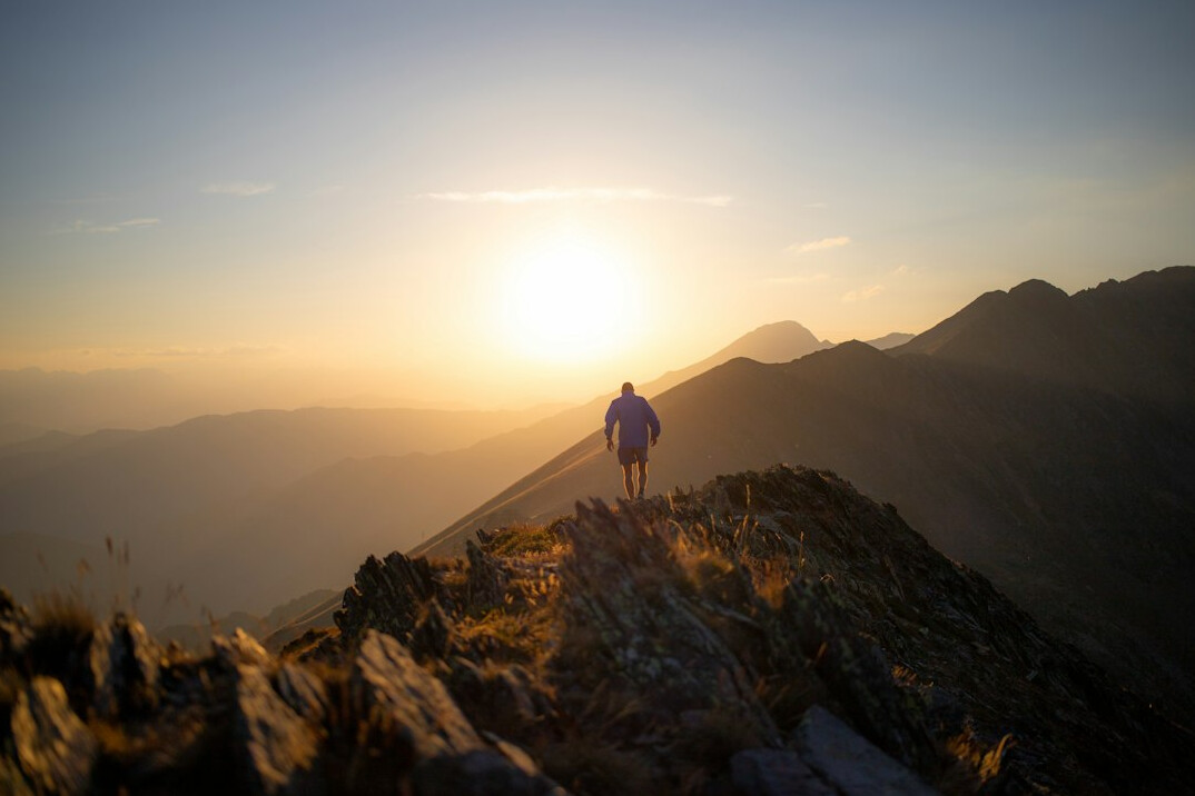 person climbing mountain at sunrise